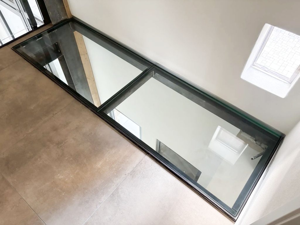 Begehbares Glas – modernes Design mit überraschend vielen Einsatzmöglichkeiten 3 Begehbares Glas im Innenbereich: zweiteiliges Bodenelement in schwarzem Stahlrahmen